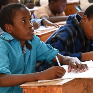 Two students writing at wooden desks in an MCF classroom
