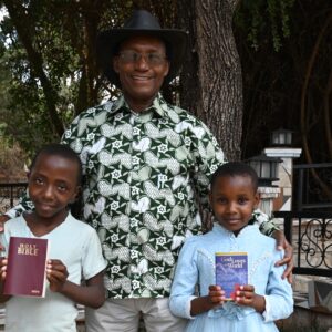 A man in a cowboy hat with two children holding a Bible and a booklet
